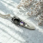 Talismán artesanal de plata con piedra luna y obsidiana
