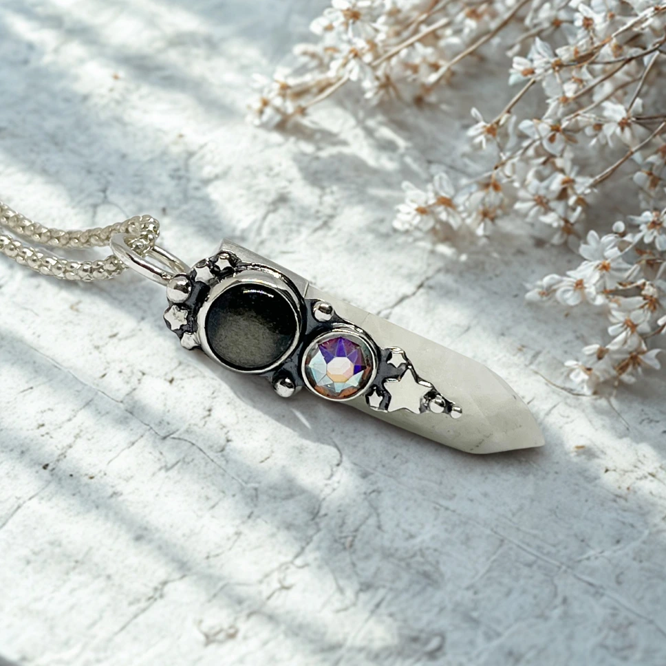 Talismán artesanal de plata con piedra luna y obsidiana