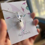 Detalle poético: colgante con colibrí, flor y cadena fina