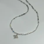 Joya simbólica con nudo de bruja y perlas