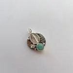 Medalla religiosa con hojas talladas y piedra en la parte inferior