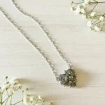 Colgante de pirita natural rodeado de pelotitas de plata