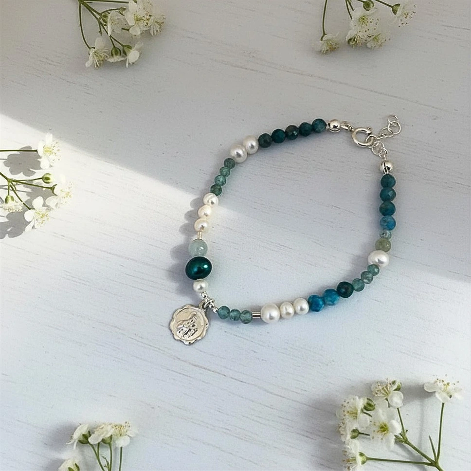 Pulsera Artesanal con Simbolismo Sagrado y Piedras Naturales – Plata 950 Pulsera femenina con apatita, aguamarina y perlas cultivadas, colgante religioso plata a elección
